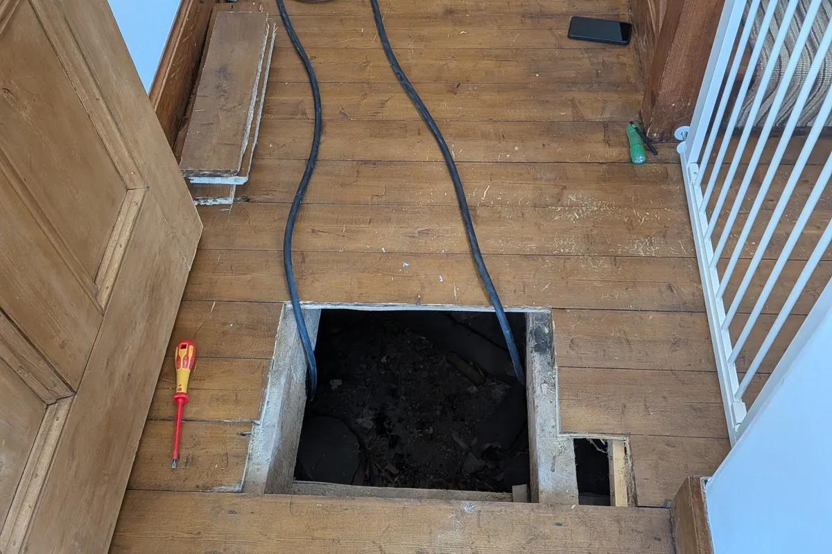 Under-floor cable routing for EV charger installation showing cables run beneath floorboards