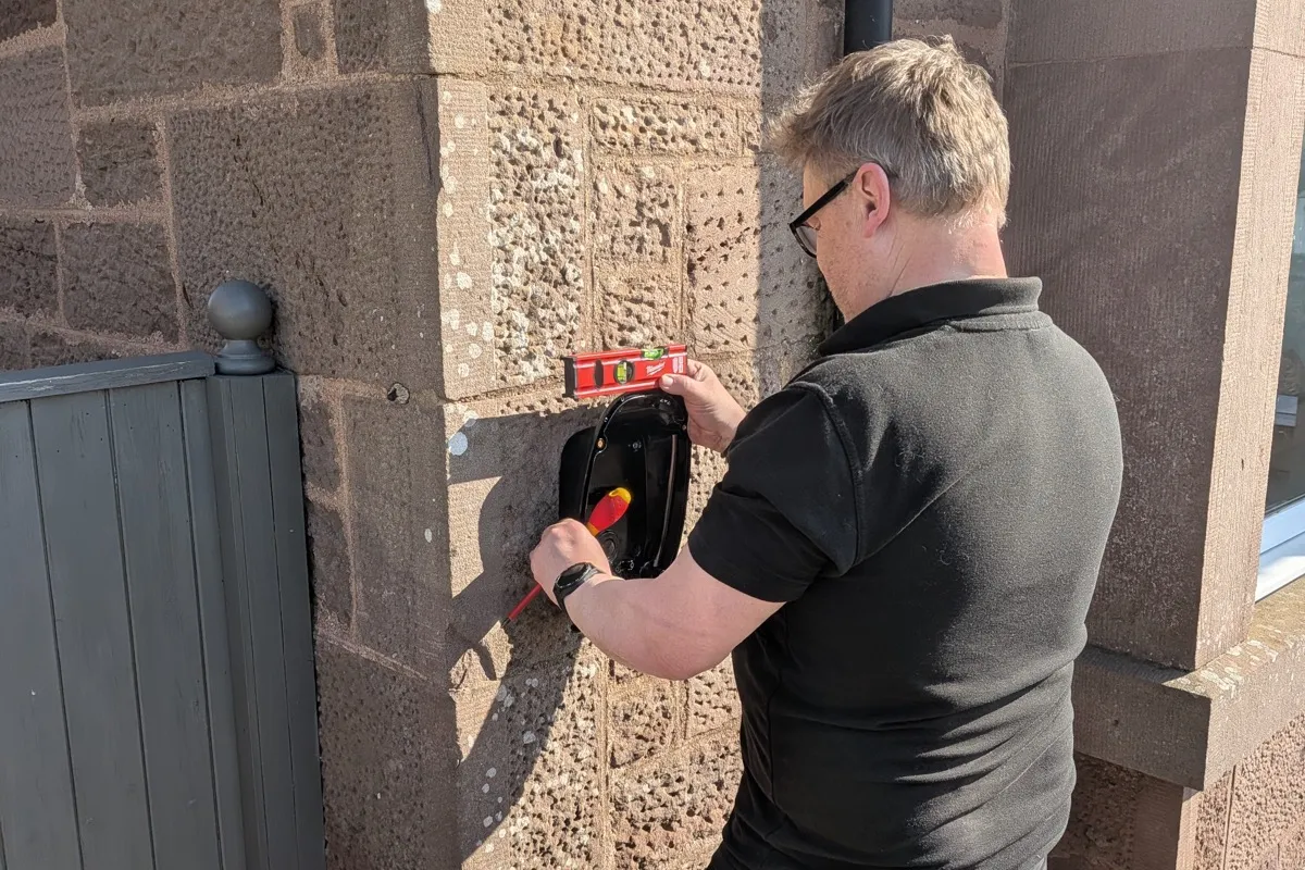 Electrician installing an EV charger on a stone wall property in Brechin, Angus