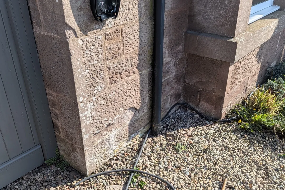 Wall-mounted EV charger installed on a stone property in Brechin with charging cable